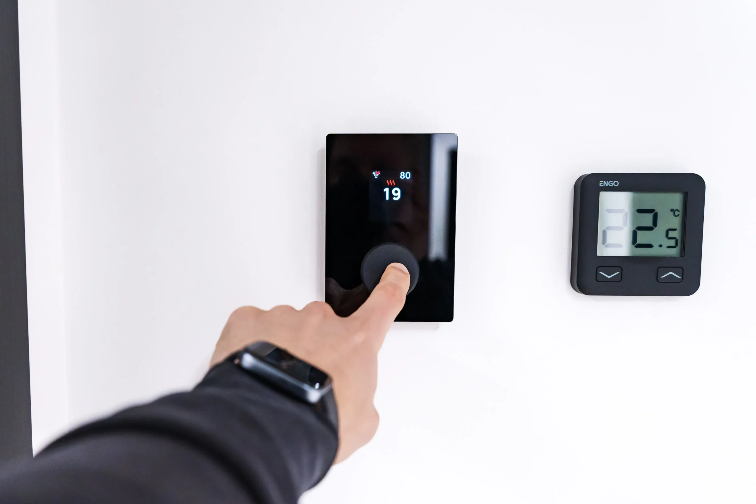 Homeowner adjusting thermostat temperature during Texas summer